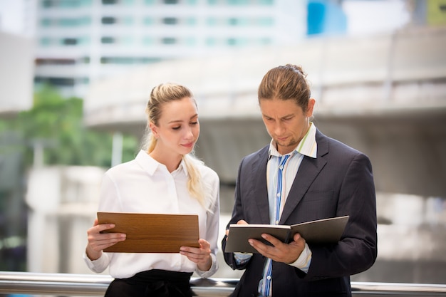 Business people discussing over clipboard and while walking outside office