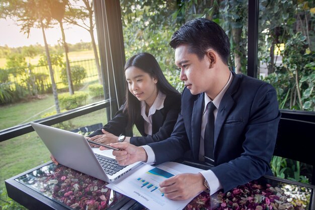 Photo business people discussing graphs while using laptop on table