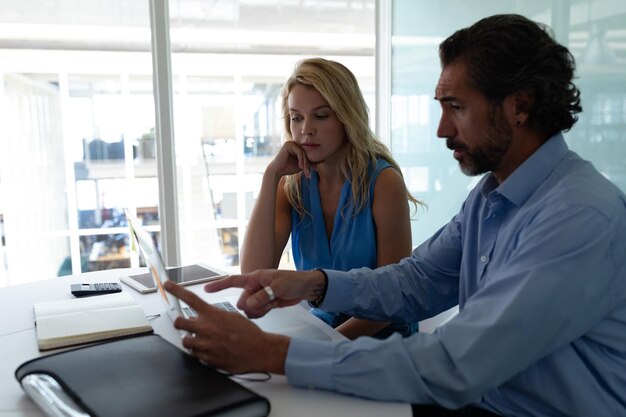 Business people discussing over laptop at desk in a modern office