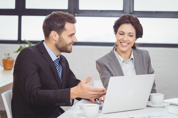 Business people discussing over laptop in meeting room