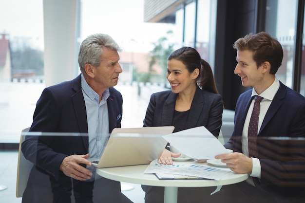 Business people discussing over laptop