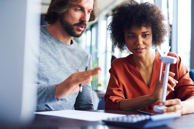 Business people discussing over windmill model