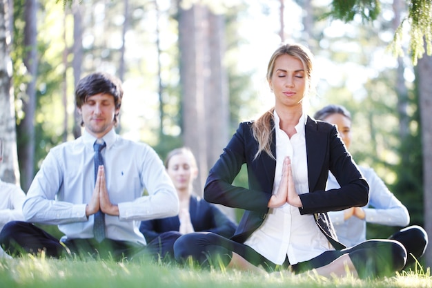 Photo business people doing yoga at the park