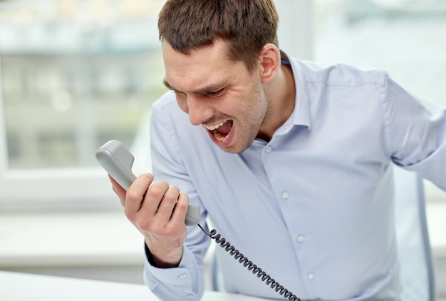 Foto affari, persone, emozioni, stress e concetto di comunicazione - uomo d'affari furioso che chiama al telefono in ufficio