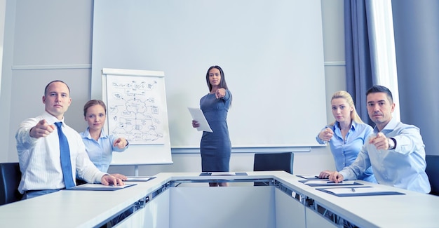 business, people en teamwork concept - groep zakenmensen die elkaar ontmoeten en met de vinger wijzen naar jou op kantoor