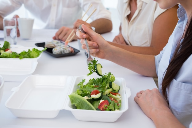 Gente di affari che gode dell'insalata e dell'insalata per pranzo