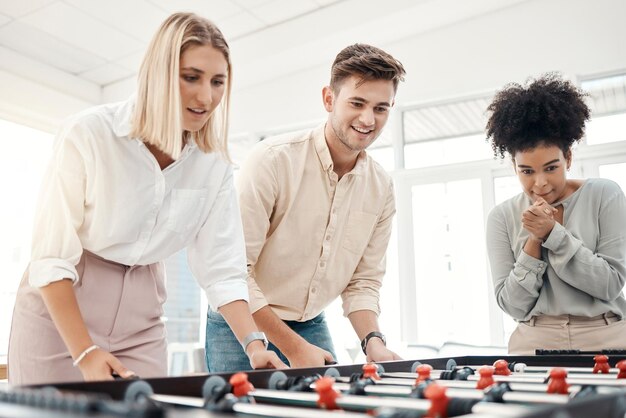 Business people foosball table and competition in office for team building motivation and teamwork in startup company Group diversity employees playing creative soccer games for fun collaboration