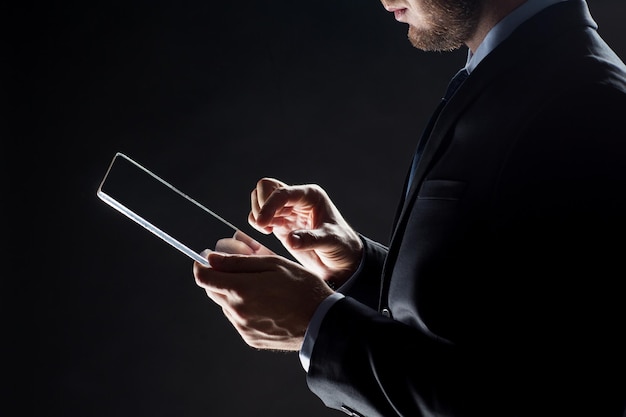 business, people and future technology concept - close up of businessman with transparent tablet pc computer over black