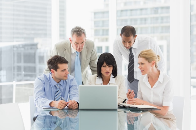 Business people gathered around laptop talking