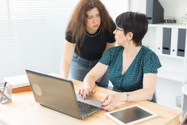 Business people and graphic designer concept - Women are discussing ideas at the office with laptop, pointing at the screen.