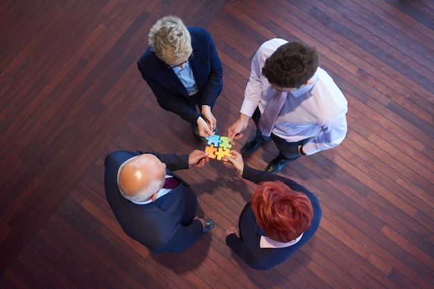 지그소 퍼즐을 조립하고 팀 지원 및 도움말 개념을 나타내는 비즈니스 사람들 그룹, 현대적인 밝은 사무실 내부의 상위 뷰