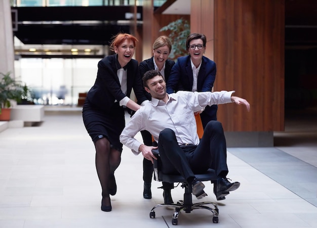 business people group at modern office indoors have fun and push office chair on corridor