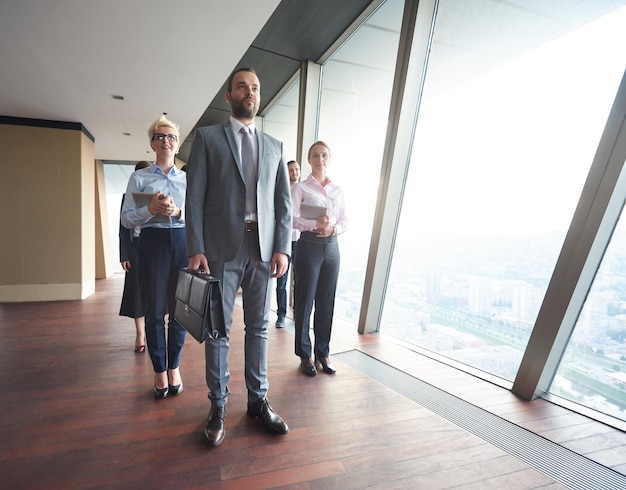 business people group standing together as team by window  in modern bright office interior