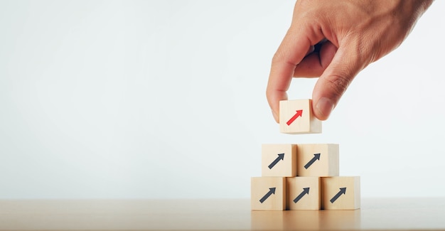 Business people hand stacked wooden blocks in stages Startup business concept Up arrow Success business growth process idea