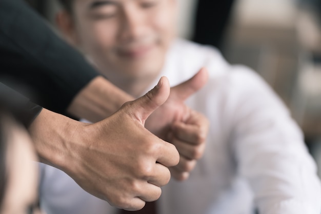 Business people hands giving thumb up in the meeting.