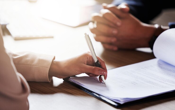 Photo business people hands and signing contract form or application for hire recruitment or policy on table hand of person writing or filling in paperwork with pen for deal agreement or information