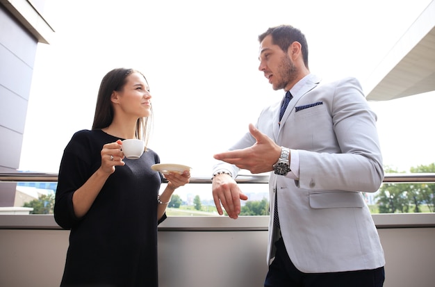 Uomini d'affari che hanno pausa sulla terrazza dell'ufficio all'aperto bere caffè parlando.