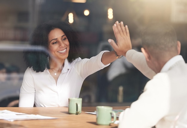 Business people high five and celebration in meeting for planning team collaboration or success at cafe Black woman touching hands with colleague for teamwork partnership or b2b at coffee shop