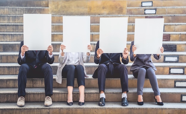 Photo business people holding billboards while sitting on steps