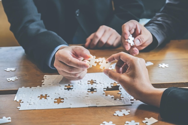 Business people holding white jigsaw puzzleconcept Relationship building brainstorming teamwork