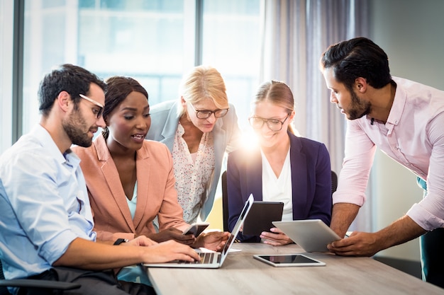 Business people interacting using laptop, mobile phone and digital tablet