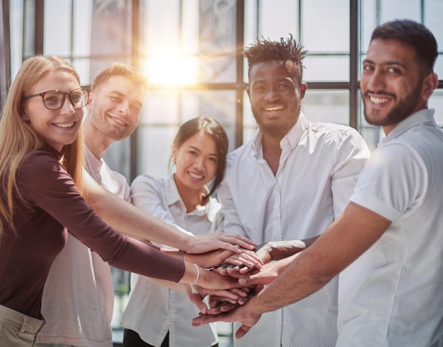 Business people joining hands in the office concept of teamwork and partnership double exposure