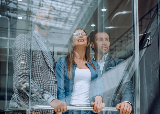 Business people in a large glass elevator in a modern\
office