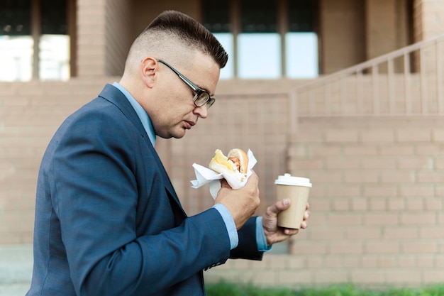 ビジネスマンのライフスタイル。コーヒーとサンドイッチはランチに持ち帰ります。仕事場に行く途中で朝食をとっているビジネスマンのためのおやつ。