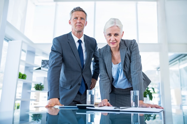 Business people looking at camera behind desk 