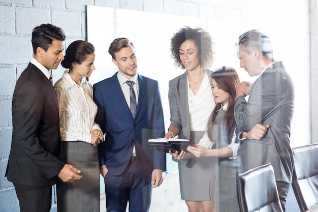 business people looking in diary and interacting in conference room