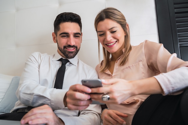 Business people lying on bed and using mobile phone