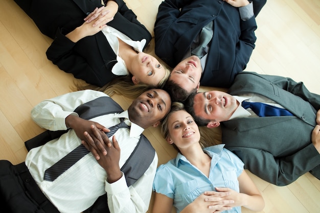 Business people lying in a circle on the floor