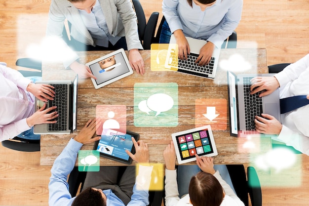 business, people, media and technology concept - close up of creative team with laptop and tablet pc computers sitting at table in office