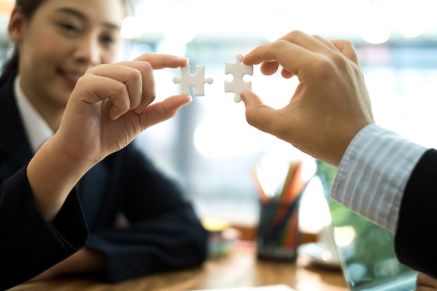 business people meeting brainstorming and  using white puzzle pieces being fitted togethe