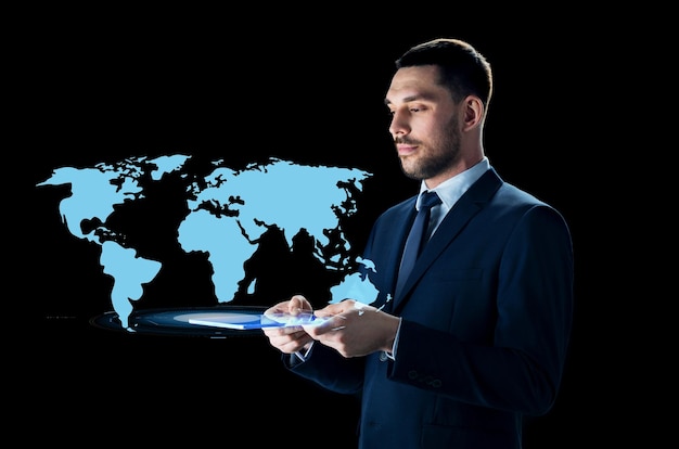 business, people and modern technology concept - businessman in suit with transparent tablet pc computer and world map projection over black background