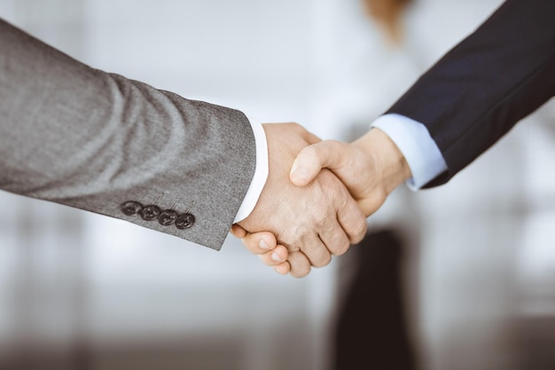 Business people in office suits standing and shaking hands, close-up. Business communication concept. Handshake and marketing.