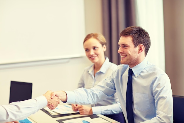 business, people and partnership concept - smiling business team shaking hands in office