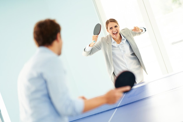 business people playing table tennis in shared office space