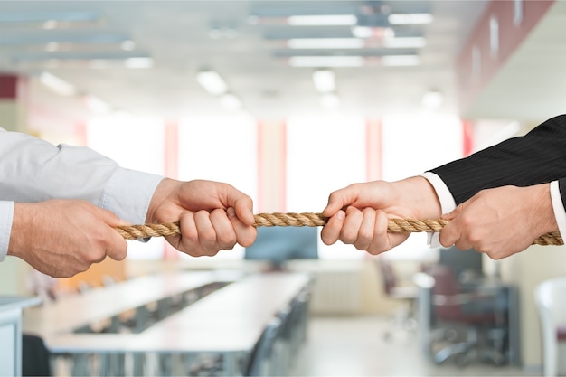 Photo business people pulling rope in opposite directions at office