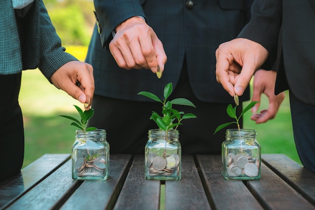 Business people put coin to money saving glass jar Gyre