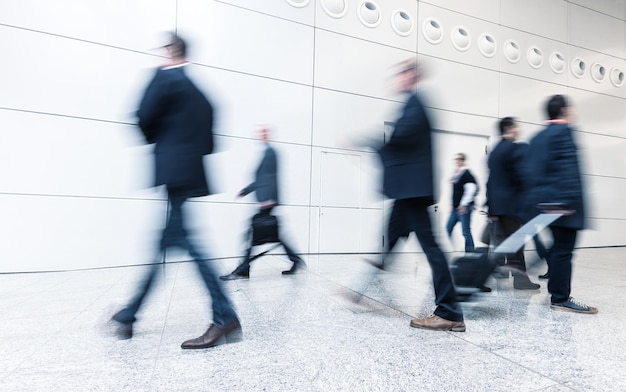 Uomini d'affari che si precipitano in un corridoio in un business center. ideale per layout di siti web e riviste