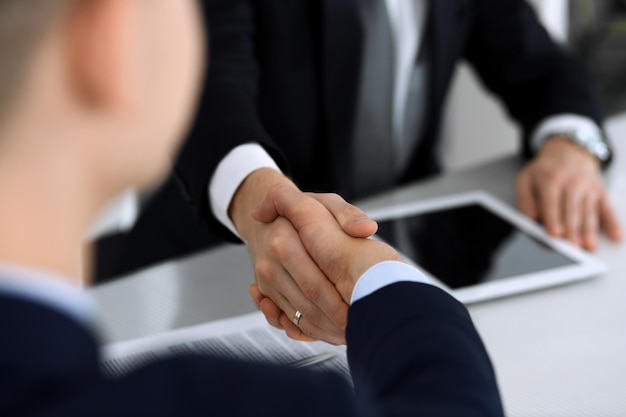 Фото Деловые люди пожимают друг другу руки после подписания контракта за стеклянным столом в современном офисе