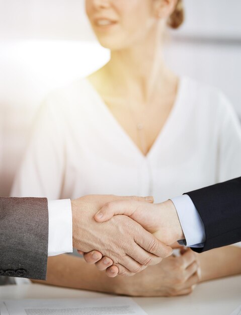 Business people shaking hands finishing contract signing in sunny office, close-up. Handshake and marketing.