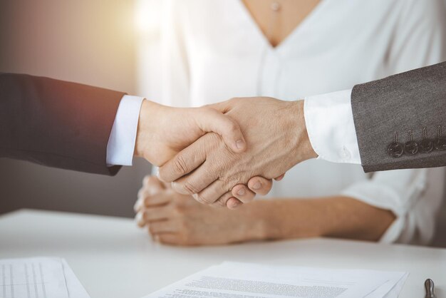 Business people shaking hands finishing contract signing in sunny office, close-up. Handshake and marketing.