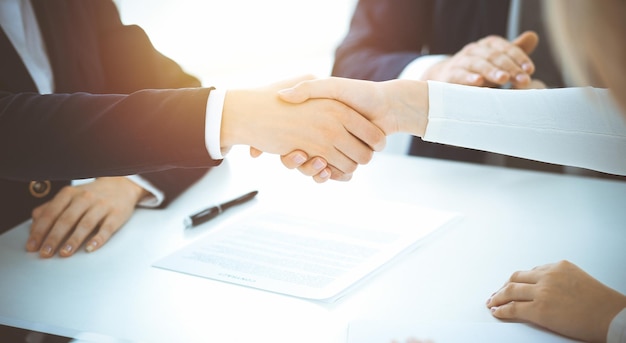 Business people shaking hands finishing up meeting or negotiation in sunny office. Business handshake and partnership concepts.