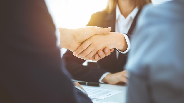 Business people shaking hands finishing up meeting or negotiation in sunny office Business handshake and partnership concepts