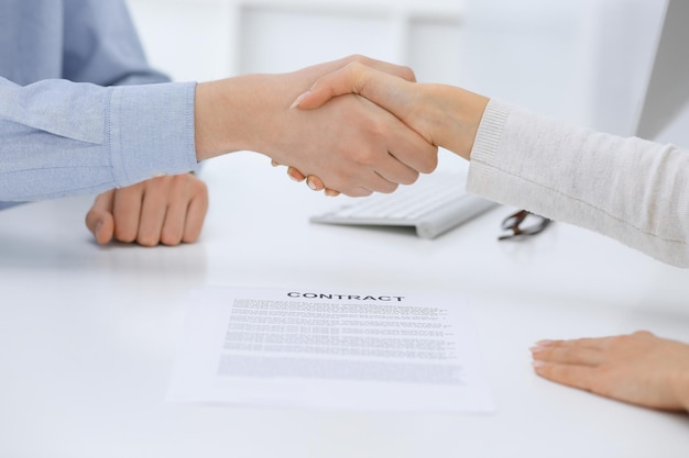 Business people shaking hands at meeting or negotiation after contract discussing Businessman and woman handshake at office while sitting at the desk Success concept