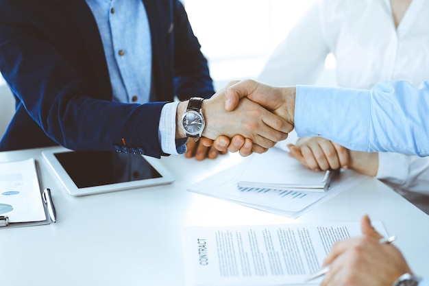 Photo business people shaking hands at meeting or negotiation, close-up. group of unknown businessmen and women in modern office. teamwork, partnership and handshake concept, toned picture