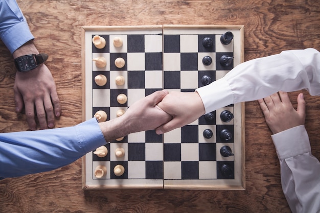 Business people shaking hands. Playing chess game