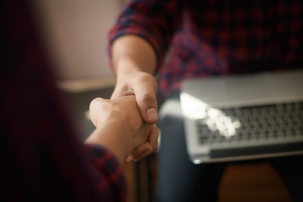 Photo business people shaking hands while sitting at the working place finish success business good deals meeting partnership